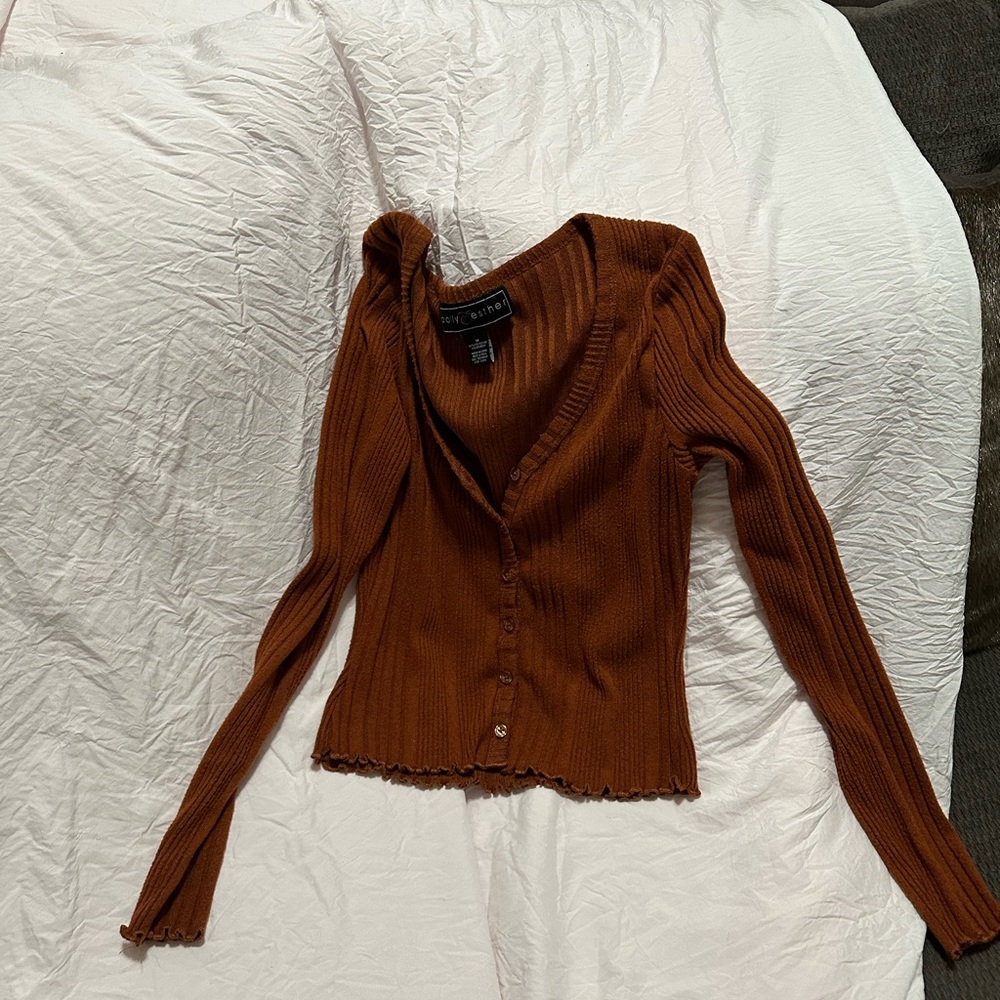 A simple burnt orange cardigan that has six buttons and ruffles at the end.